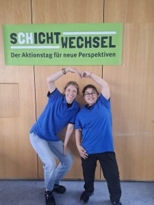 Zwei Menschen mit und ohne Beeinträchtigung formen mit den Armen ein Herz zum Zeichen des Aktionstages "Schichtwechsel".